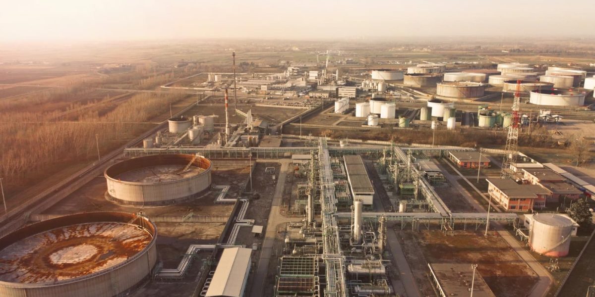 Widok z lotu ptaka na rafinerię ze zbiornikami paliwa i instalacją rurociągową o zachodzie słońca